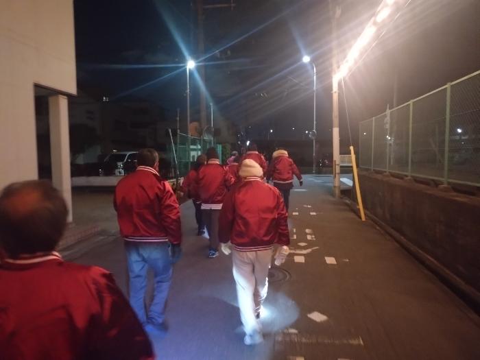 えんじ色の上着を着用した青少年指導員たちが十日戎にて街頭指導をおこなっている様子（夜）