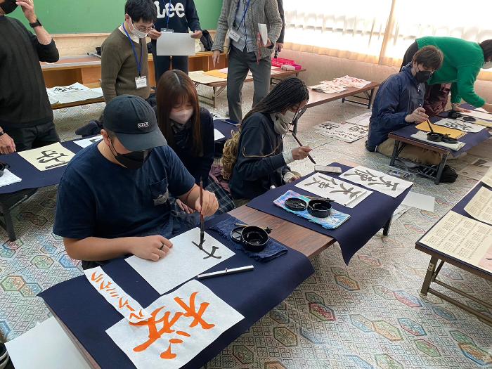 カルバーシティ市の高校生たちが貝塚高校書道部と書道交流をする様子  「桜」や「天使」などの字を毛筆で書いている