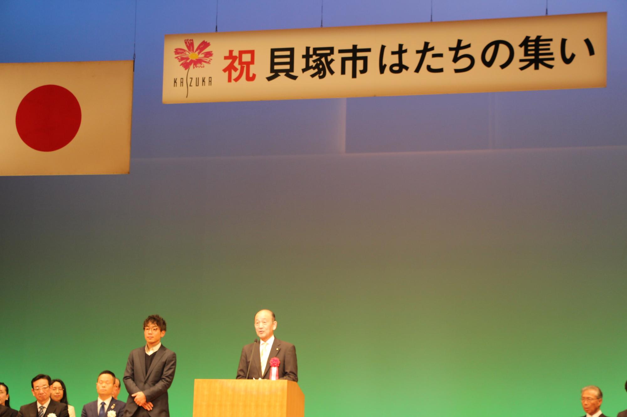 コスモスシアター大ホール舞台上にて市議会議長があいさつをしている様子
