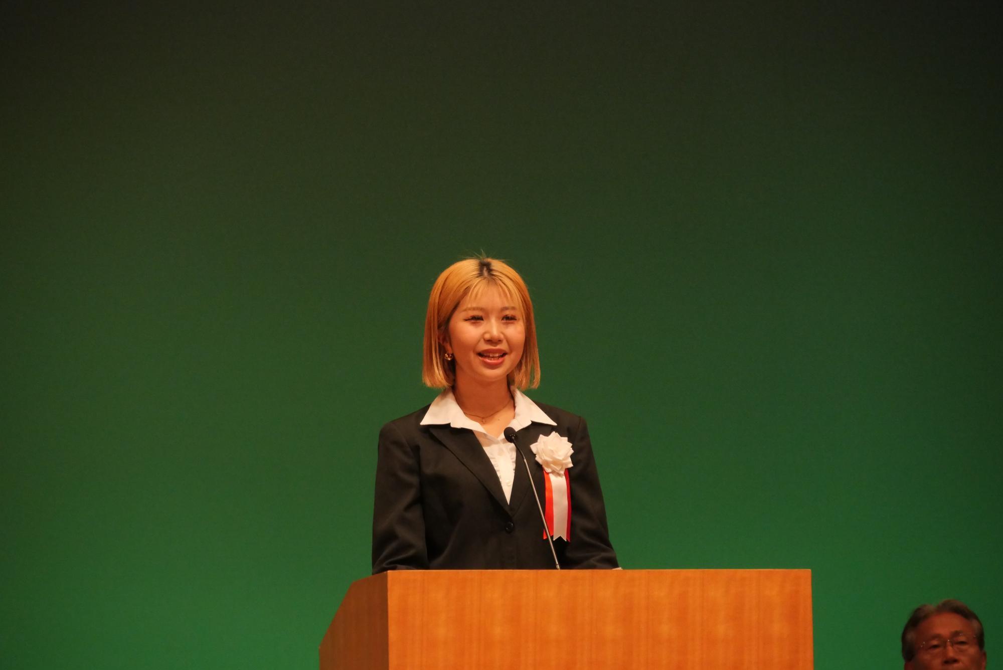 コスモスシアター大ホール舞台上にてはたちの集い実行委員長があいさつをしている様子