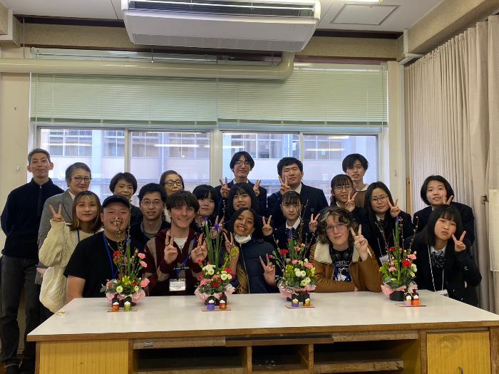 カルバーシティ市の高校生たちが、貝塚南高校華道部、生徒会の皆さんの集合写真を撮影しました。（机の上にはカルバーシティ市の高校生たちの作品が飾られている）