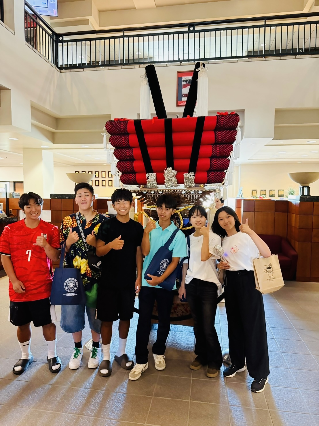 カルバーシティ市役所玄関ホールにある太鼓台の前でカルバーシティ市と貝塚市の高校生たちがならんで撮っている写真