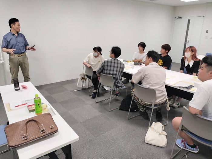 全体会議で講師の講義を学生が聞いている様子