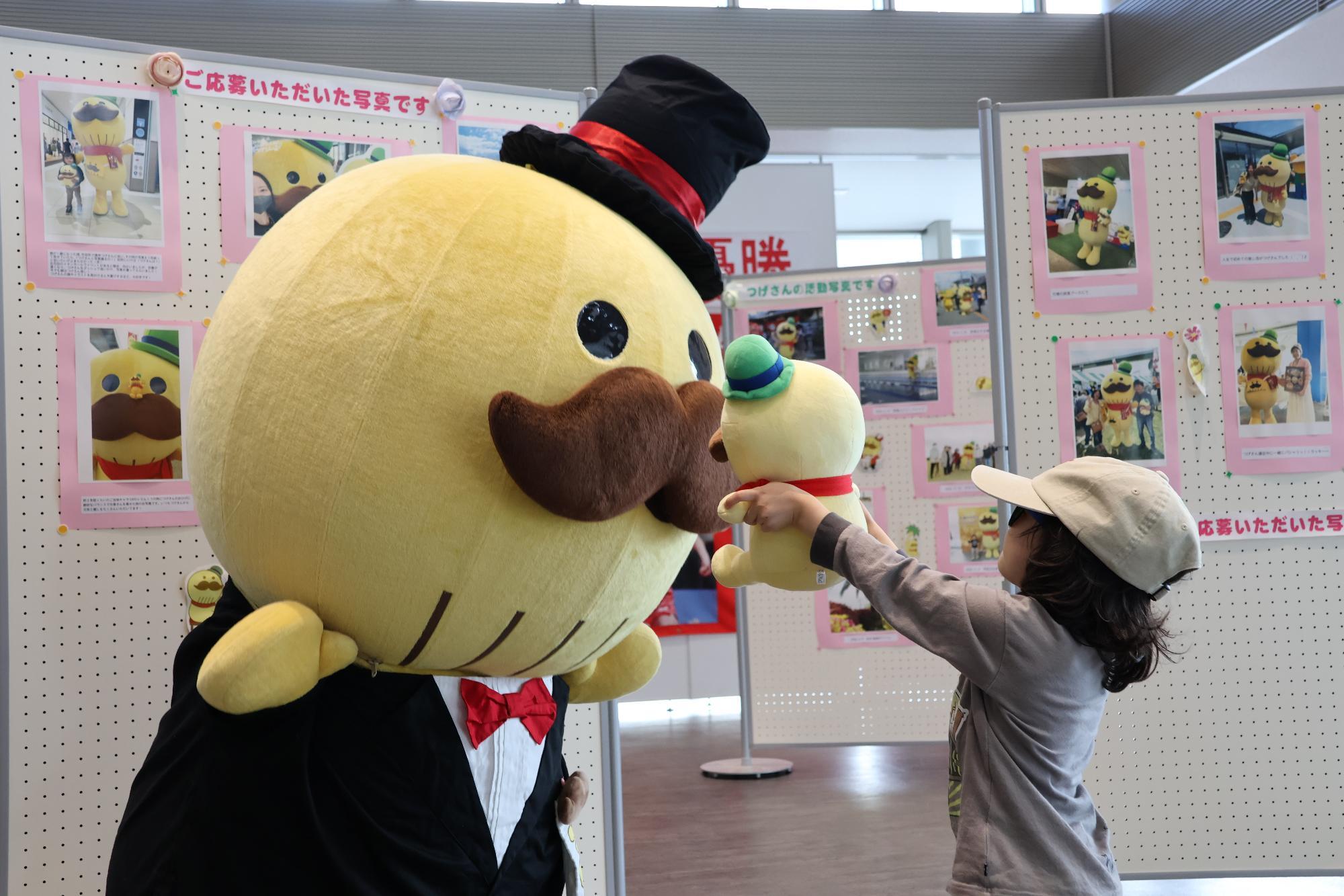 つげさんファンの女の子がぬいぐるみをつげさんに見せている写真です