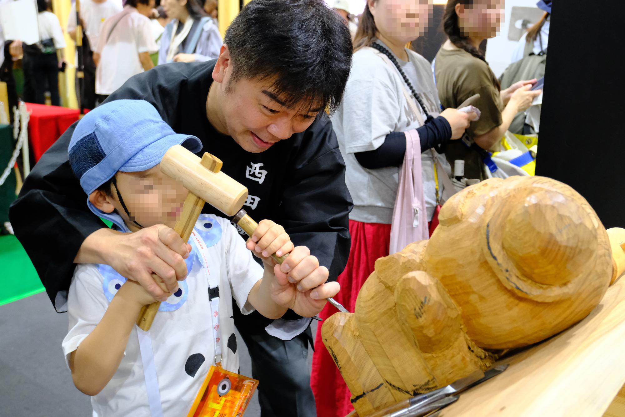 職人と来場者の木彫り体験の様子