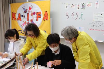 ふれあい交流祭りというイベントでかいづか国際交流協会の会員が外国籍のゲストにちぎり絵を教えています