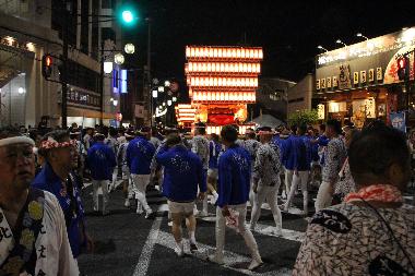 夜の太鼓台祭りの写真です。太鼓台の提灯が輝き、夜の道を照らします。